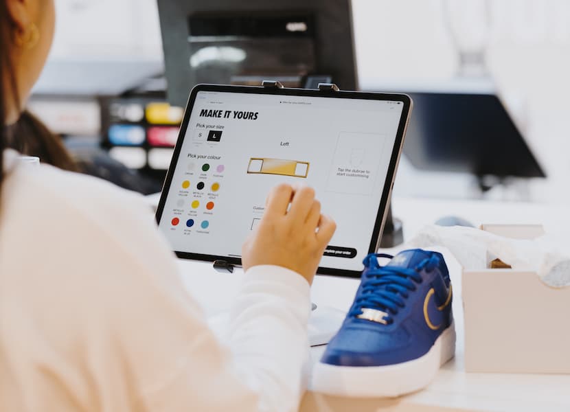 A woman designs a custom shoe on a tablet, showcasing creativity and technology in footwear design.